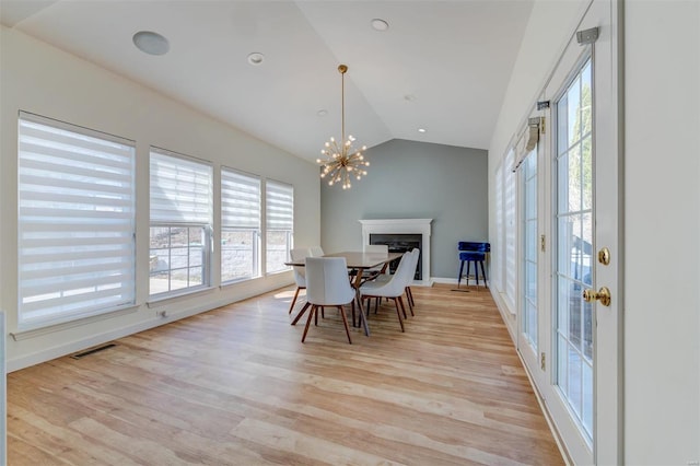 dining space featuring an inviting chandelier, vaulted ceiling, light wood-style floors, and visible vents