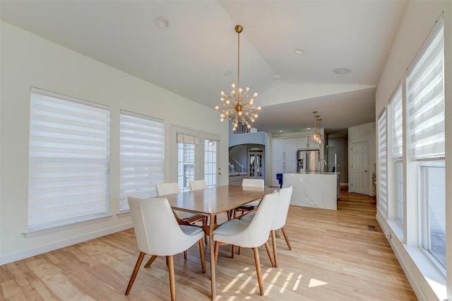 dining room featuring vaulted ceiling, a notable chandelier, arched walkways, and light wood-type flooring