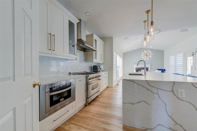 kitchen with a sink, appliances with stainless steel finishes, wall chimney exhaust hood, and a healthy amount of sunlight