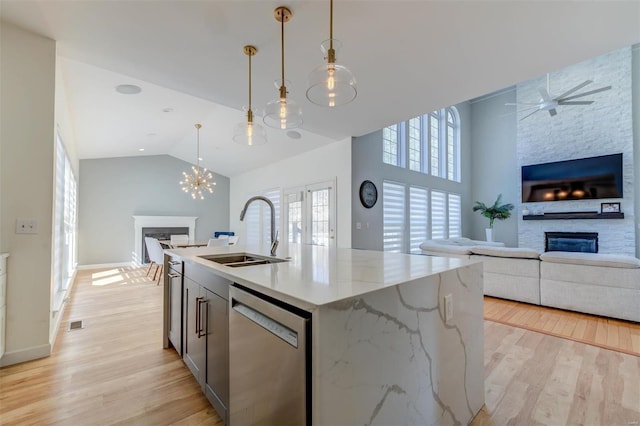 kitchen with a sink, open floor plan, light wood-style floors, a stone fireplace, and dishwasher