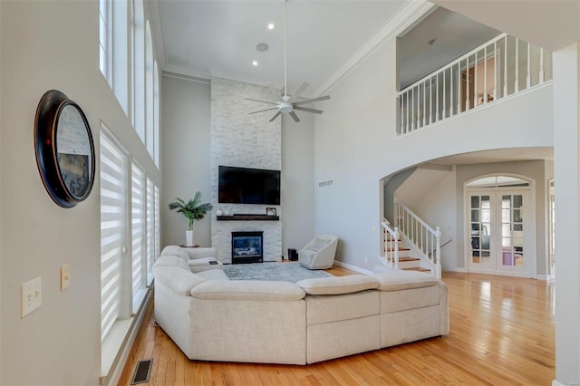 living area featuring a wealth of natural light, visible vents, and ornamental molding