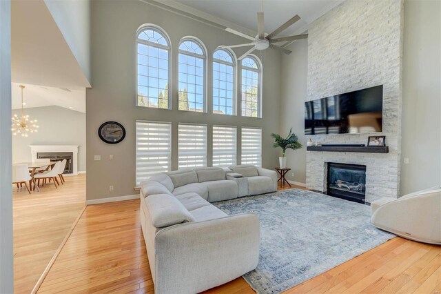 living room with a stone fireplace, plenty of natural light, baseboards, and wood-type flooring