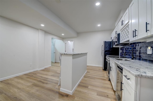 kitchen featuring light wood-style flooring, recessed lighting, white cabinets, appliances with stainless steel finishes, and backsplash