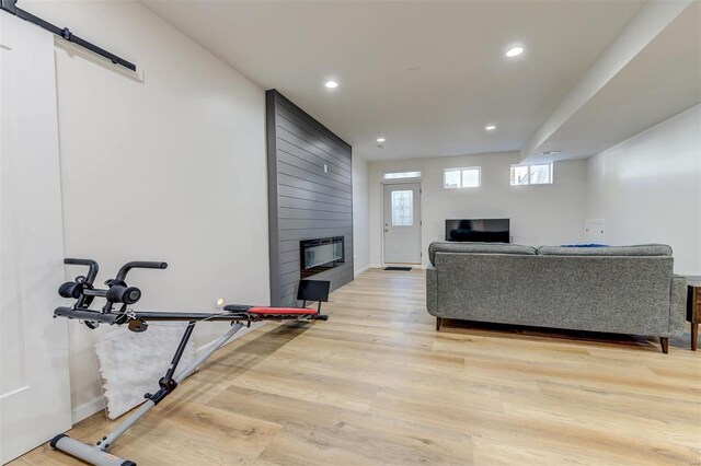 living room featuring light wood-type flooring, a barn door, recessed lighting, and a fireplace