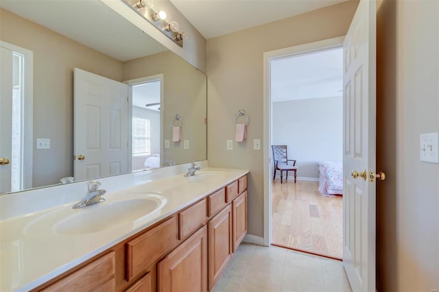 bathroom featuring double vanity, connected bathroom, baseboards, and a sink