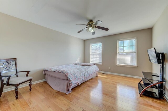 bedroom with light wood finished floors, ceiling fan, and baseboards