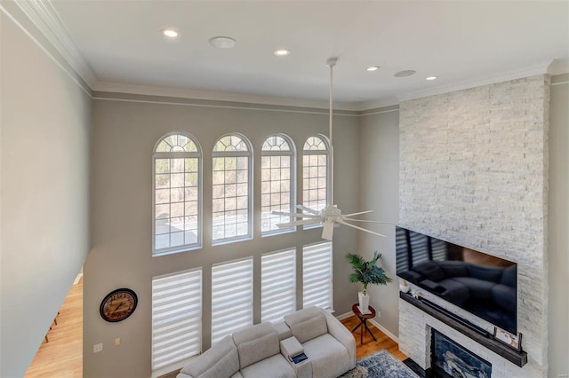 living area with ceiling fan, ornamental molding, recessed lighting, a fireplace, and wood finished floors