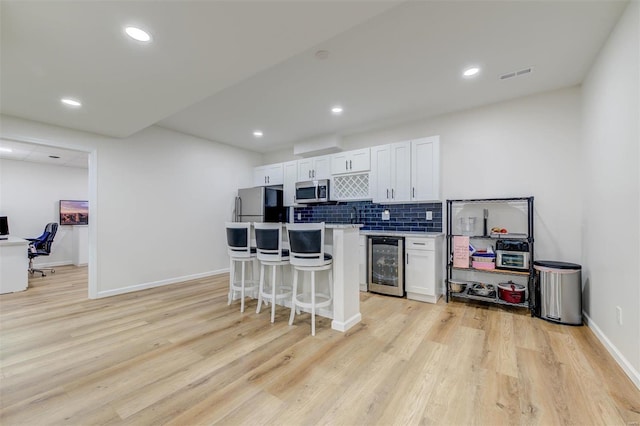 kitchen with visible vents, stainless steel appliances, decorative backsplash, wine cooler, and white cabinetry