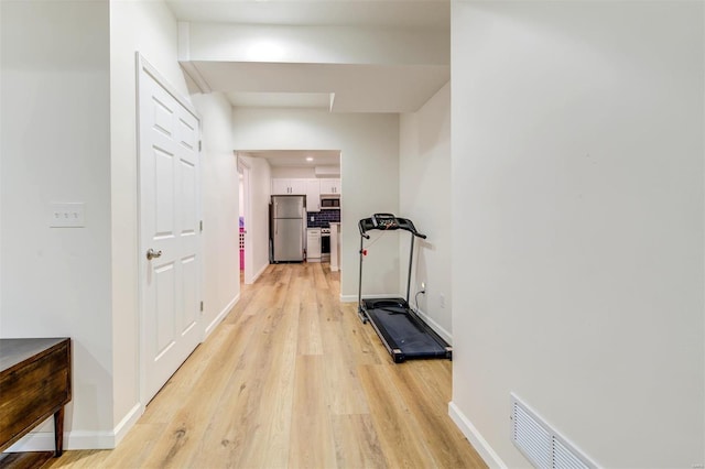 exercise room with visible vents, baseboards, and light wood finished floors