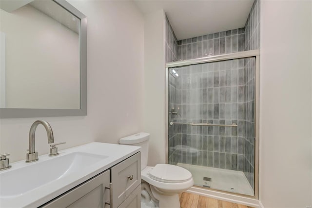 full bath featuring vanity, toilet, wood finished floors, and a stall shower