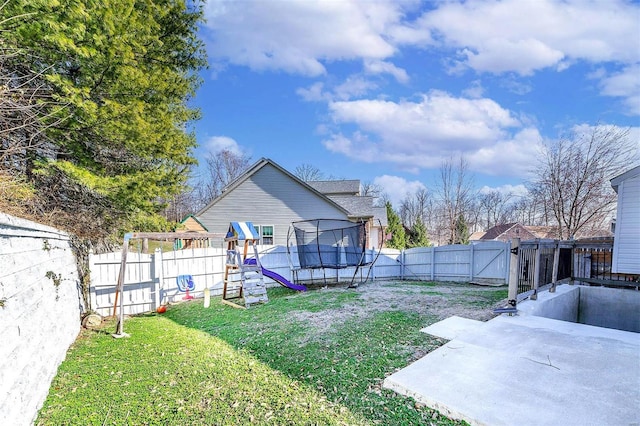 view of yard with a trampoline, a fenced backyard, and a playground