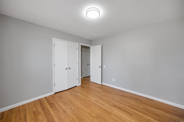 unfurnished bedroom with a closet, light wood-type flooring, and baseboards