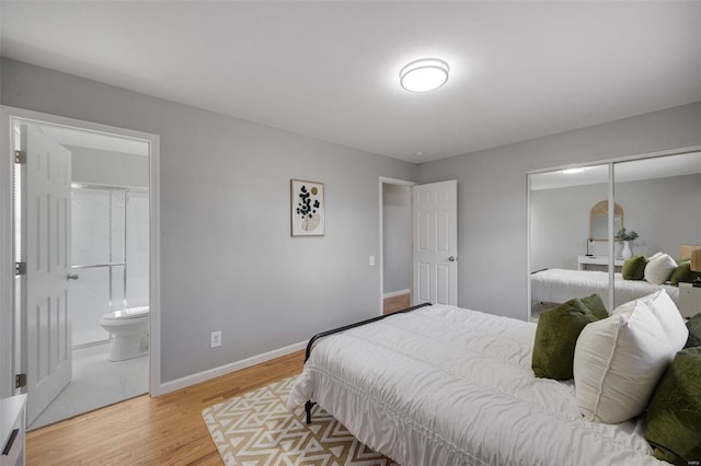 bedroom featuring a closet, baseboards, light wood finished floors, and connected bathroom