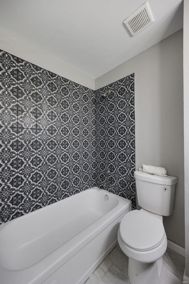 bathroom featuring toilet, a bathtub, visible vents, and baseboards