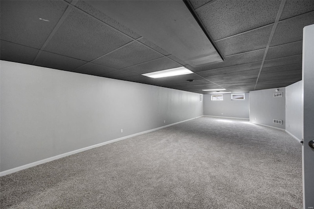 below grade area with visible vents, baseboards, a drop ceiling, and carpet floors