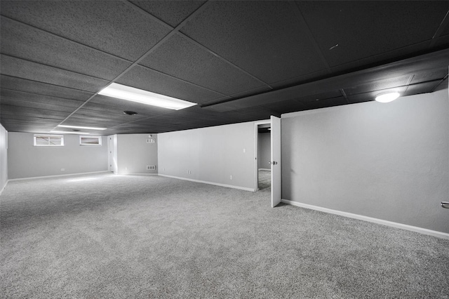 below grade area with a paneled ceiling, baseboards, and carpet