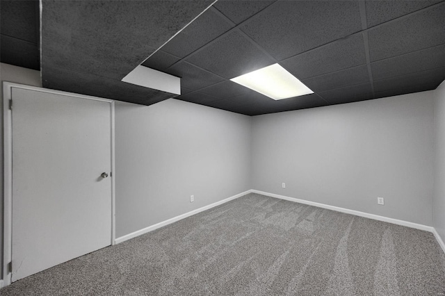 finished below grade area featuring a drop ceiling, carpet floors, and baseboards