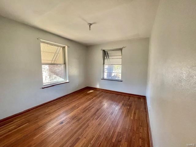 spare room with baseboards and wood finished floors