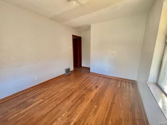 unfurnished room with visible vents, baseboards, and wood finished floors