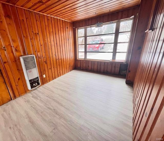 unfurnished room with heating unit, wooden walls, wood ceiling, and wood finished floors