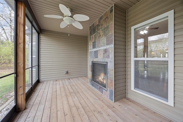 unfurnished sunroom featuring plenty of natural light, a large fireplace, and a ceiling fan