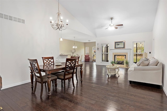 dining space featuring high vaulted ceiling, baseboards, ceiling fan with notable chandelier, visible vents, and dark wood-type flooring