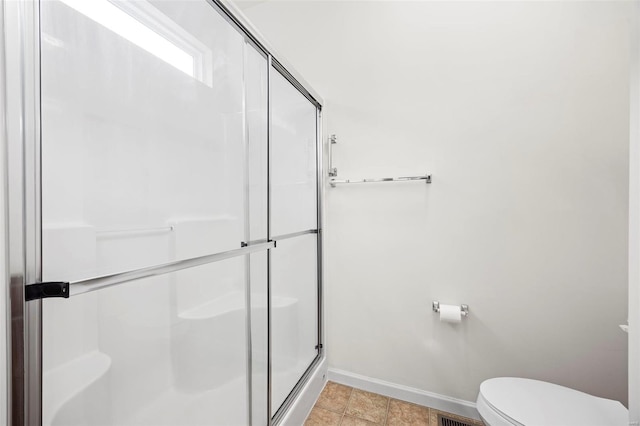 bathroom with toilet, a stall shower, and baseboards