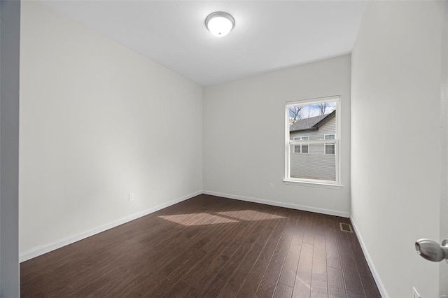 spare room featuring dark wood-style floors, baseboards, and visible vents
