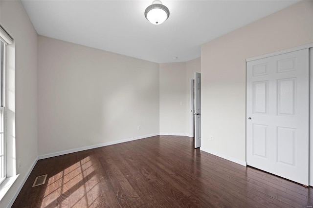 spare room featuring dark wood-type flooring, baseboards, and visible vents