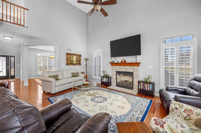 living area featuring a fireplace, wood finished floors, a healthy amount of sunlight, and ceiling fan