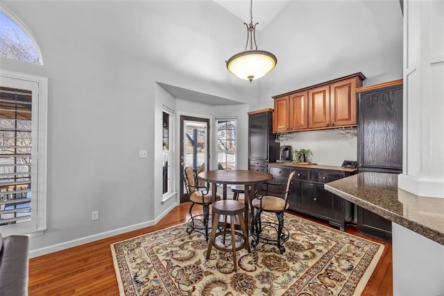 dining area with baseboards, high vaulted ceiling, and wood finished floors