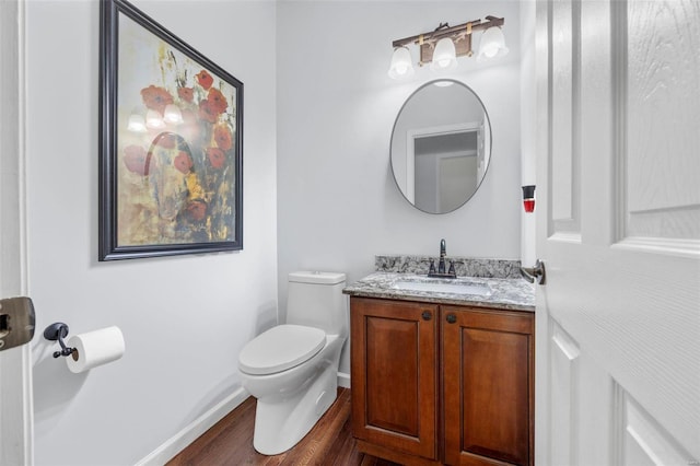 bathroom featuring baseboards, toilet, wood finished floors, and vanity