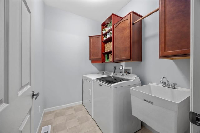 clothes washing area featuring visible vents, a sink, cabinet space, baseboards, and washing machine and clothes dryer