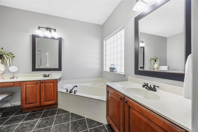 bathroom with tile patterned floors, two vanities, a garden tub, and a sink