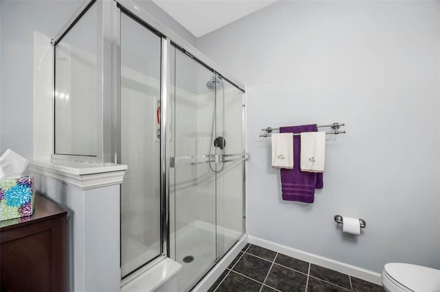 bathroom with tile patterned floors, toilet, baseboards, and a stall shower