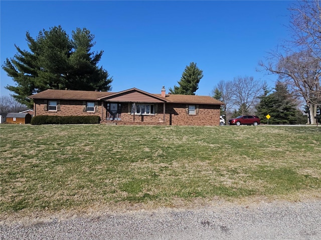 ranch-style house featuring brick siding, a chimney, and a front yard