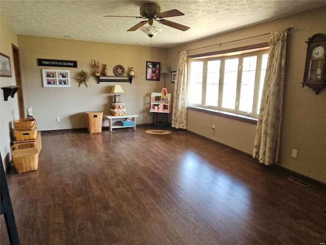 interior space featuring a ceiling fan, wood finished floors, baseboards, and a textured ceiling