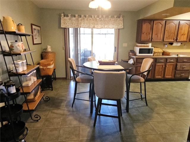 dining room with baseboards and dark tile patterned flooring