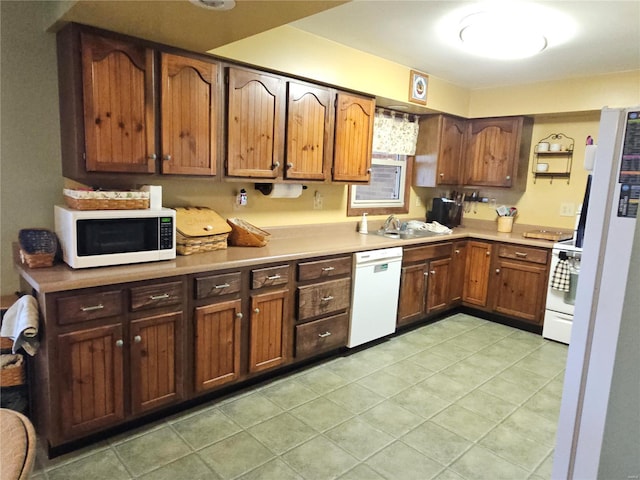 kitchen featuring white appliances, light tile patterned floors, light countertops, and brown cabinets