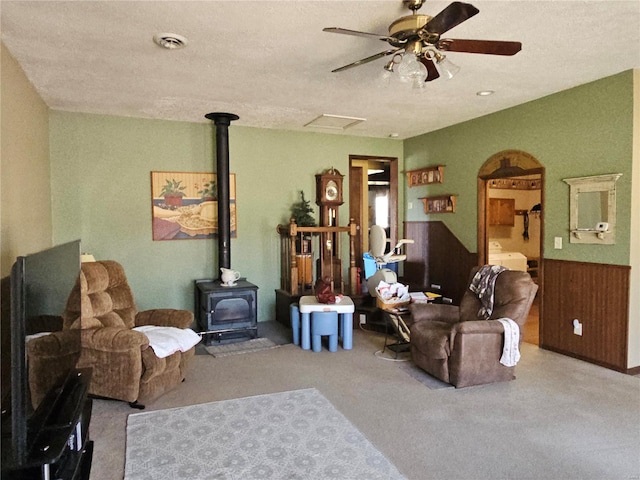 living area with visible vents, carpet floors, wood walls, wainscoting, and a wood stove