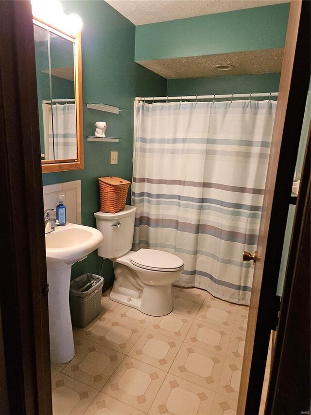 full bath with curtained shower, toilet, and a textured ceiling