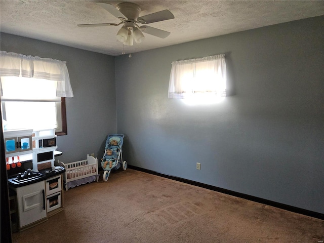 interior space with ceiling fan, a textured ceiling, baseboards, and carpet floors