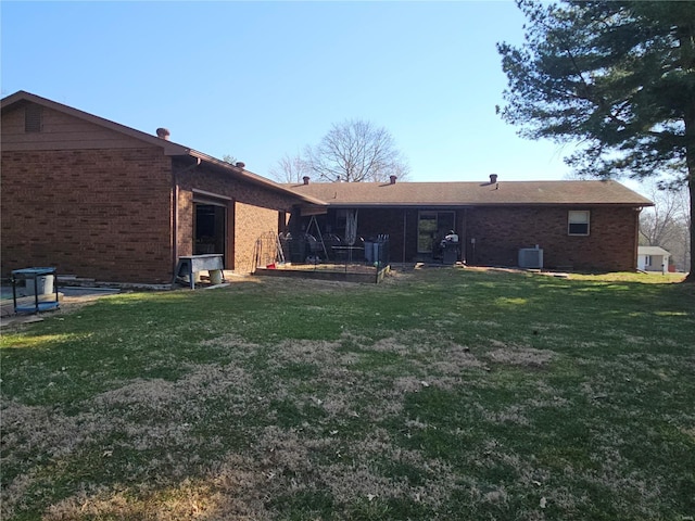 back of property featuring a yard, cooling unit, and brick siding