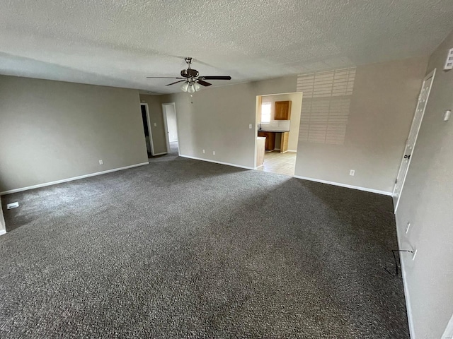 interior space with a textured ceiling, carpet, baseboards, and ceiling fan