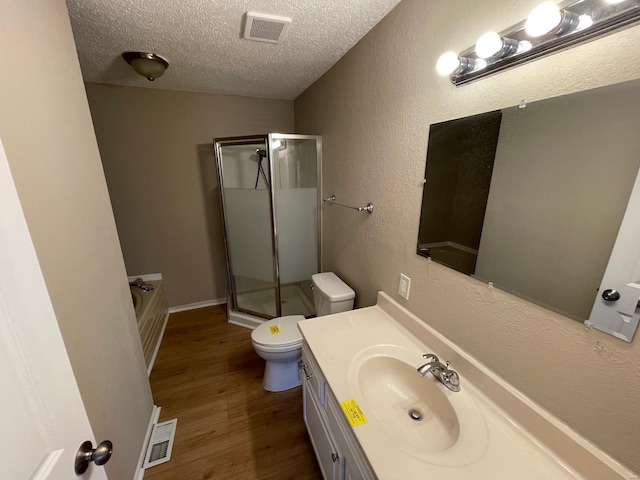 bathroom with visible vents, a textured ceiling, wood finished floors, and a shower stall