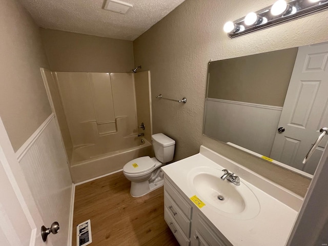 bathroom with visible vents, toilet, a textured ceiling, wood finished floors, and vanity