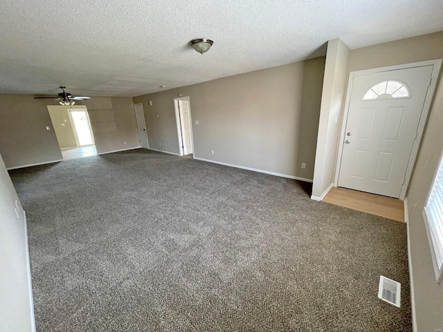 interior space with visible vents, baseboards, a textured ceiling, and ceiling fan