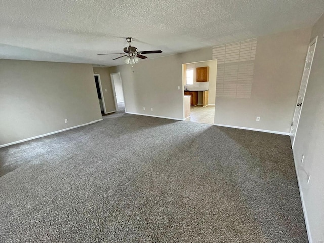 carpeted empty room featuring a textured ceiling, baseboards, and ceiling fan