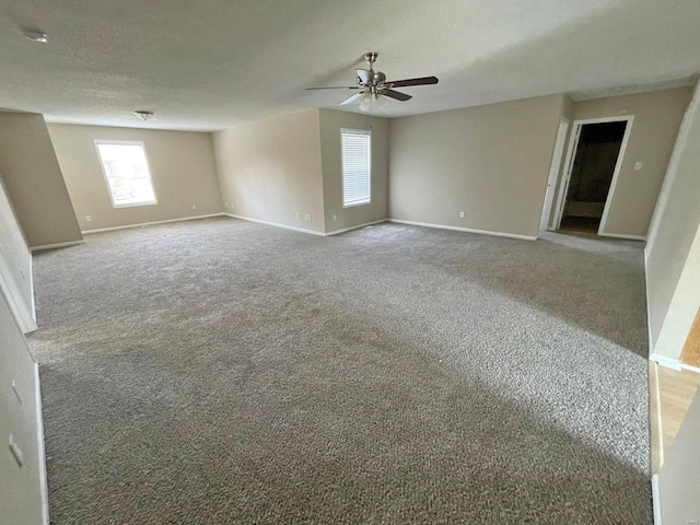 carpeted empty room with baseboards, a textured ceiling, and a ceiling fan