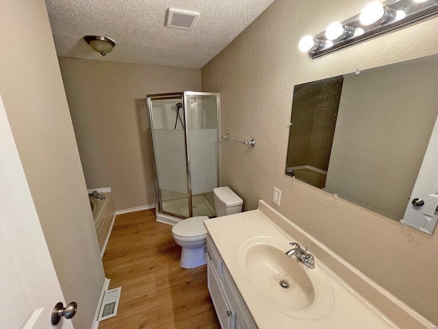 full bath with a shower stall, wood finished floors, visible vents, and a textured ceiling